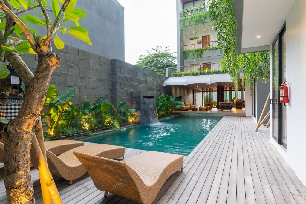 a swimming pool with chairs and a building at Casacotta in Seminyak