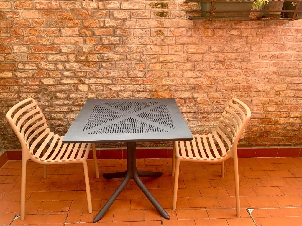 een tafel met twee stoelen naast een bakstenen muur bij appartamento con cortile in Venetië