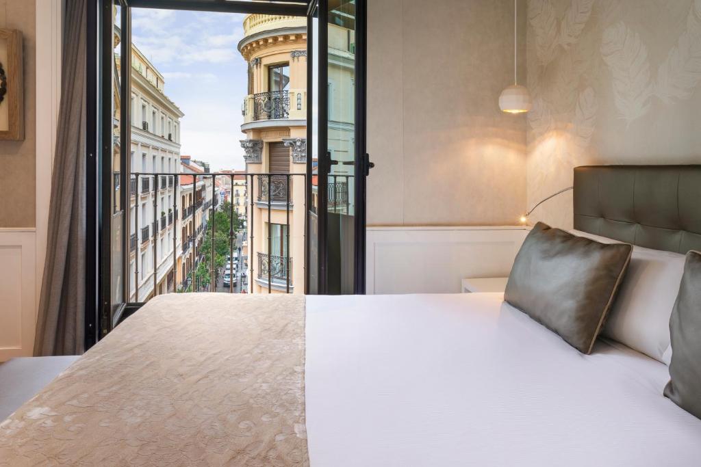 um quarto com uma cama e uma grande janela em Catalonia Puerta del Sol em Madrid