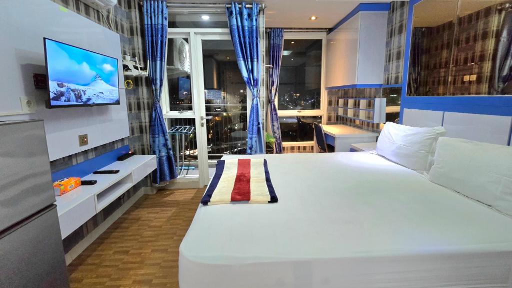 ein Schlafzimmer mit einem großen weißen Bett und einem TV in der Unterkunft Studio10 Elpis Kemayoran JIEXPO Sunrise View -Min Stay 3 nights- in Jakarta