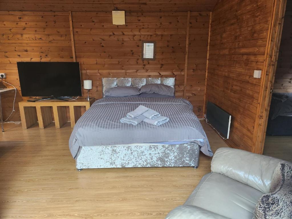 a bedroom with a bed and a tv and a couch at Southernwood - Family Lodge in Didcot
