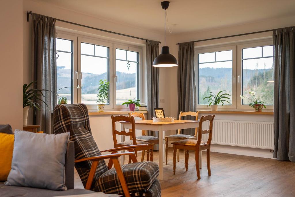 - un salon avec une table, des chaises et des fenêtres dans l'établissement Ferienwohnung Vergissmeinnicht Sauerland, à Schmallenberg