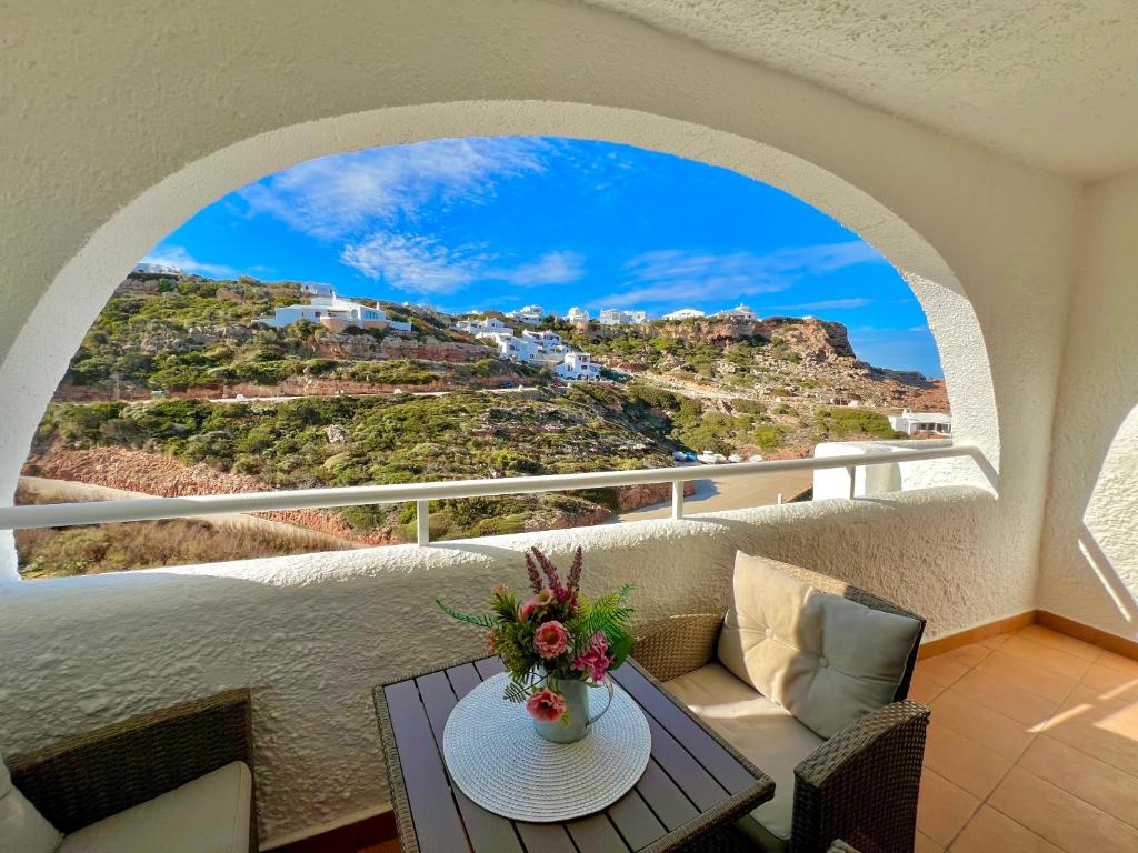 a balcony with a table and a view of a mountain at Beachfront Apartment in Cala Morell in Cala Morell