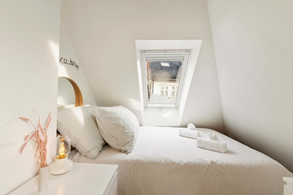 a white bedroom with a bed and a window at Dinbnb Apartments I 100 meters from Bryggen I Self check-in I Coffee + in Bergen