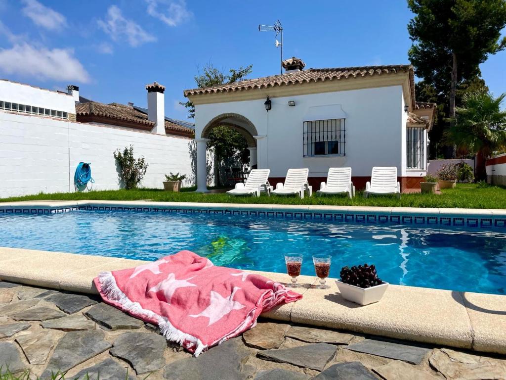 una piscina con una mesa y dos copas de vino en Chalet Manku, en Chiclana de la Frontera