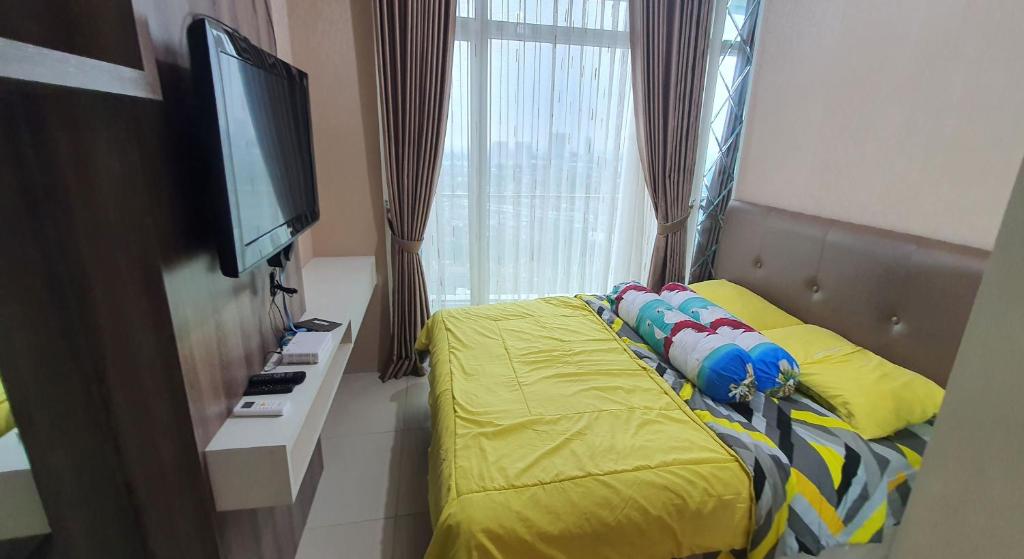 a bedroom with a bed and a tv and a window at TreeParkCity apartments by WinsHome in Tangerang