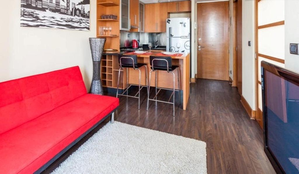 ein Wohnzimmer mit einem roten Sofa und einer Küche in der Unterkunft Departamento en Centro Providencia in Santiago