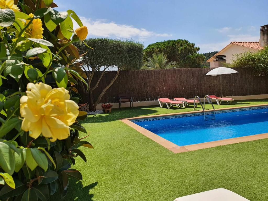 un patio trasero con piscina y césped verde en COSTA BRAVA SUITES CASA LA BAHIA piscina privada, en Platja d'Aro