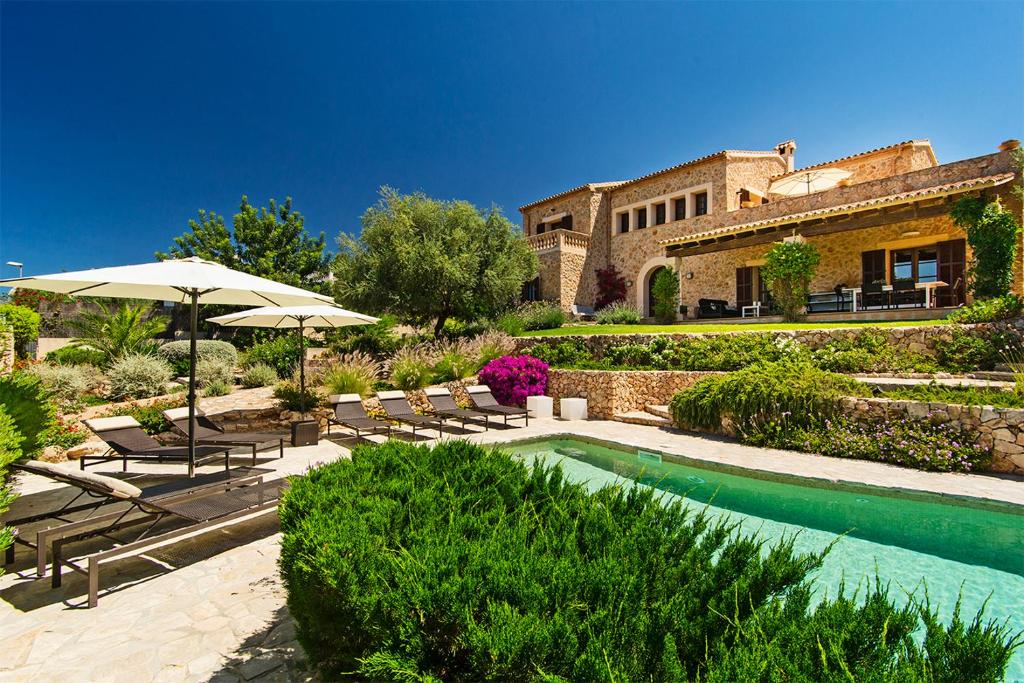 a house with a swimming pool with chairs and umbrellas at VILLA ALENAR - Marratxi- Mallorca in La Cabaneta