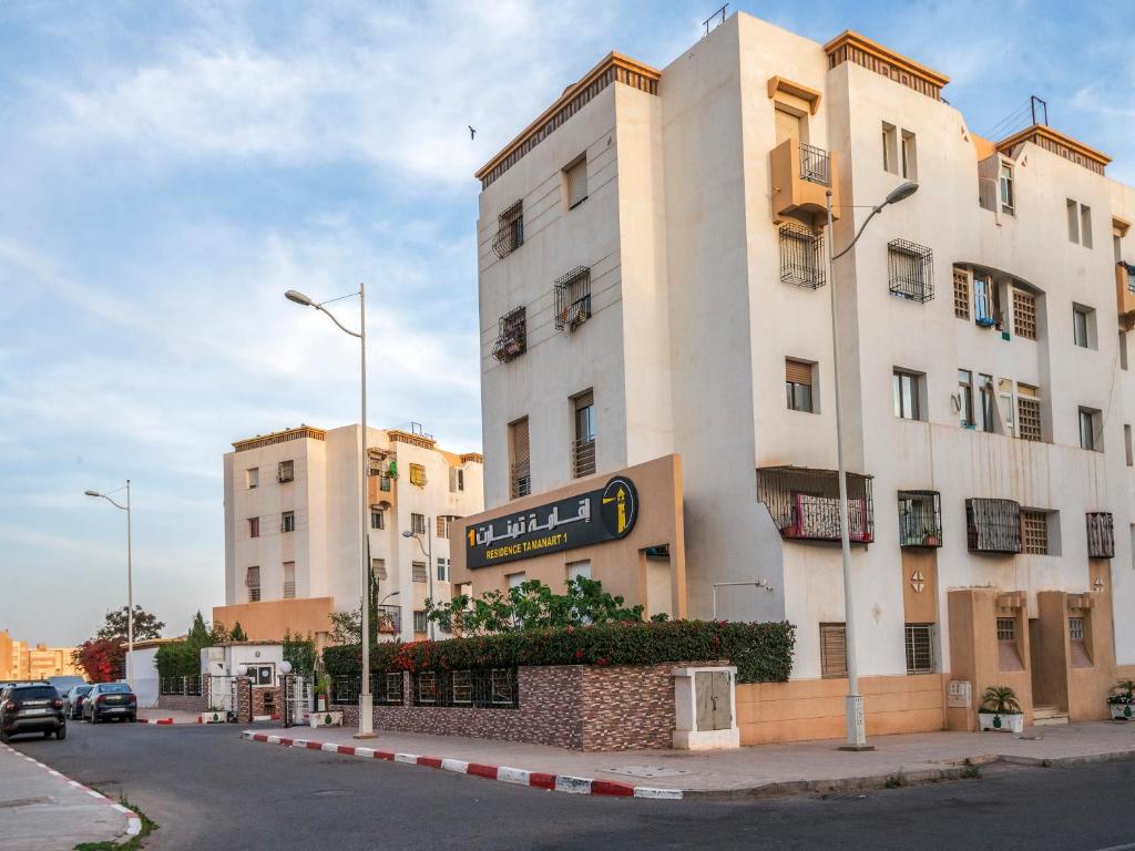- un grand bâtiment blanc avec un panneau dans l'établissement ALIYA LUXURY APARTMENT TAMANART 1-AGADIR, à Agadir