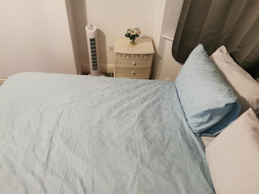 a bedroom with a bed with a blue blanket at Large Double Room Private Bathroom And SmartTV 8 in Barking