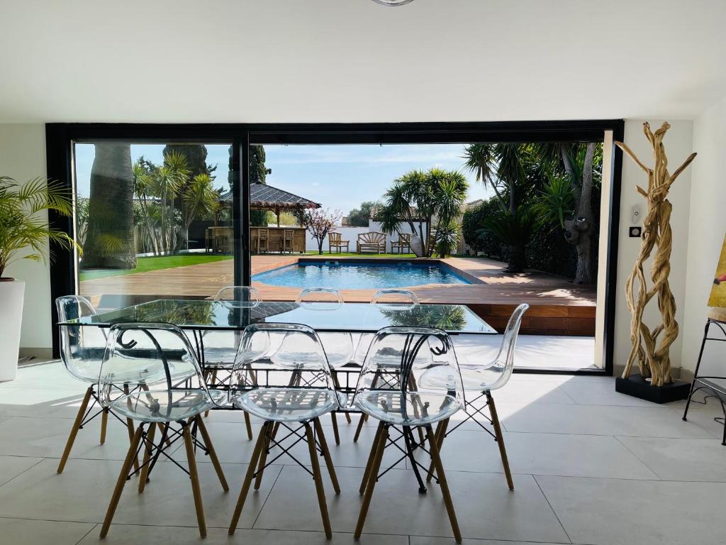 une salle à manger avec une table et des chaises et une piscine dans l'établissement Villa Bali de standing, 8 couchages à 5 min d'Arles, à Arles