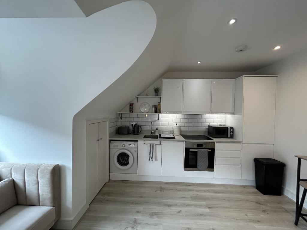 a kitchen with white cabinets and a washer at churchward house flat 4 in Chertsey