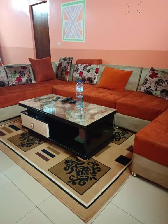 ein Wohnzimmer mit einem Sofa und einer Wasserflasche auf dem Tisch in der Unterkunft Résidence privée in Bobo-Dioulasso