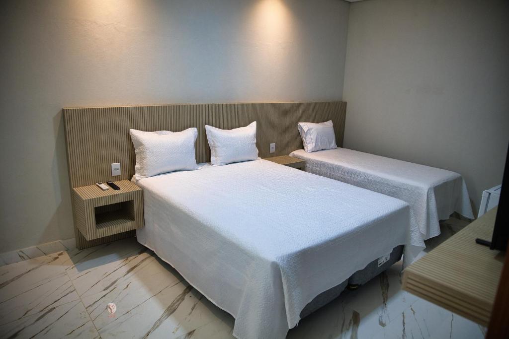 Zimmer mit 2 Betten und weißer Bettwäsche in der Unterkunft Pousada Garden das Flores in Chapada dos Guimarães