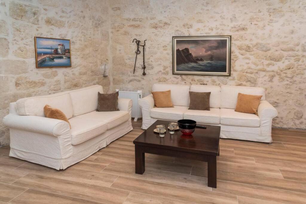 uma sala de estar com dois sofás brancos e uma mesa de centro em Victoria's House Roustika em Roústika