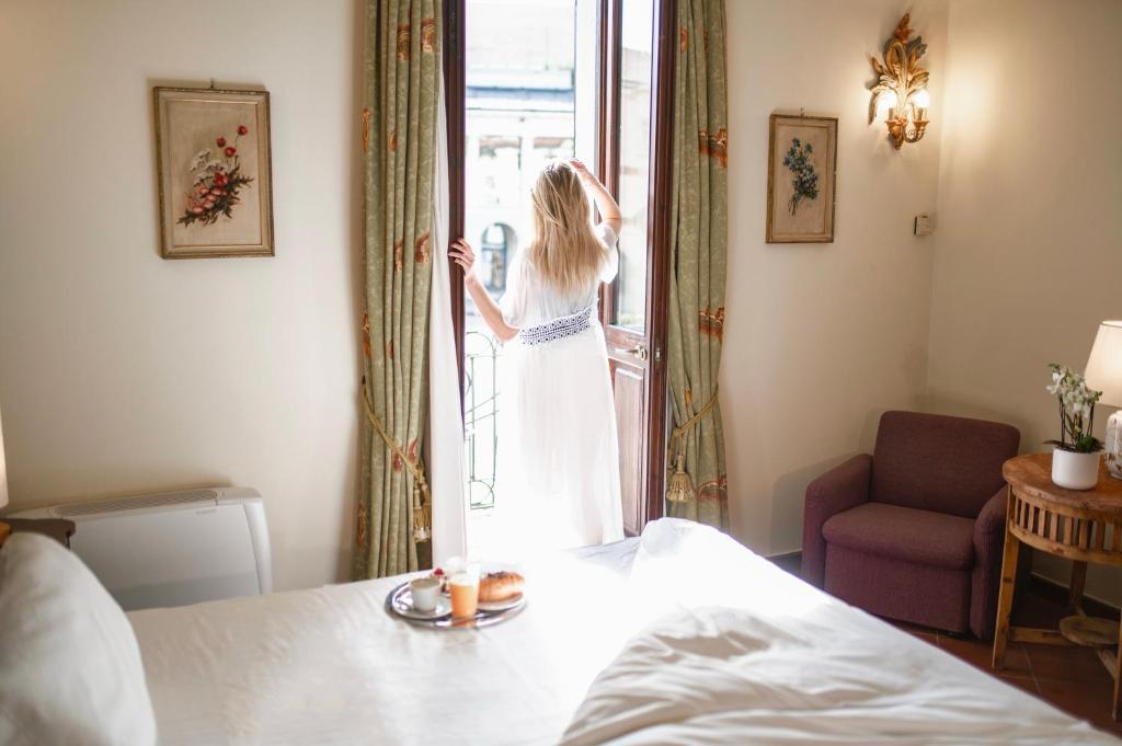 a girl is looking out the window of a bedroom at Dimora Conte Cavour in Vercelli