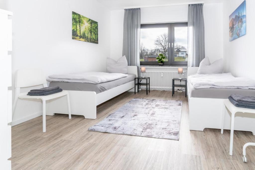 um quarto branco com 2 camas e um tapete em Moderne Ferienwohnung / Monteurswohnung mit 6 Betten in Driedorf/Herborn em Driedorf