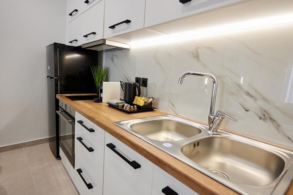 La cuisine est équipée d'un évier et d'un réfrigérateur noir. dans l'établissement Vasilicari Apartments, à Chios