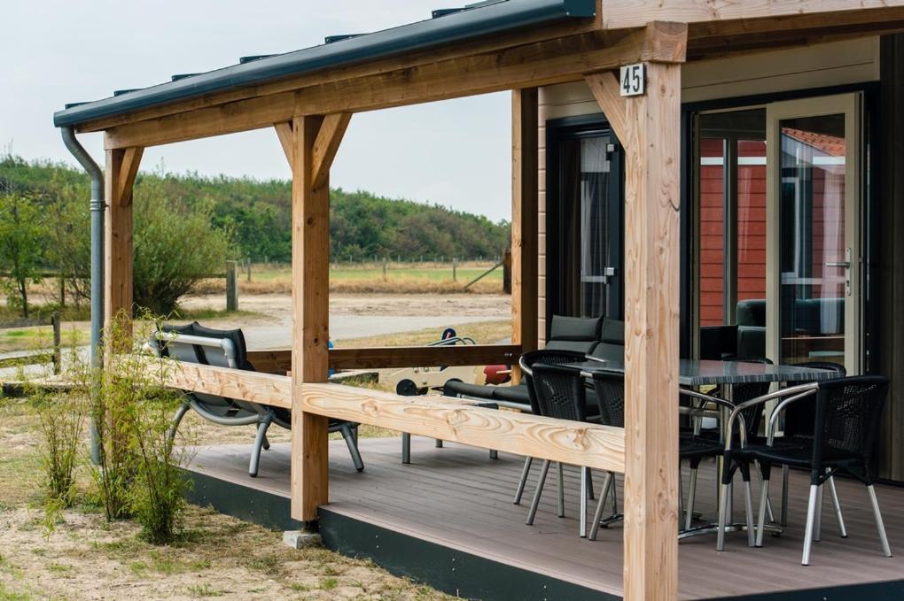 - un pavillon avec une table et des chaises sur une terrasse dans l'établissement Camping De Kiekduun, à Buren