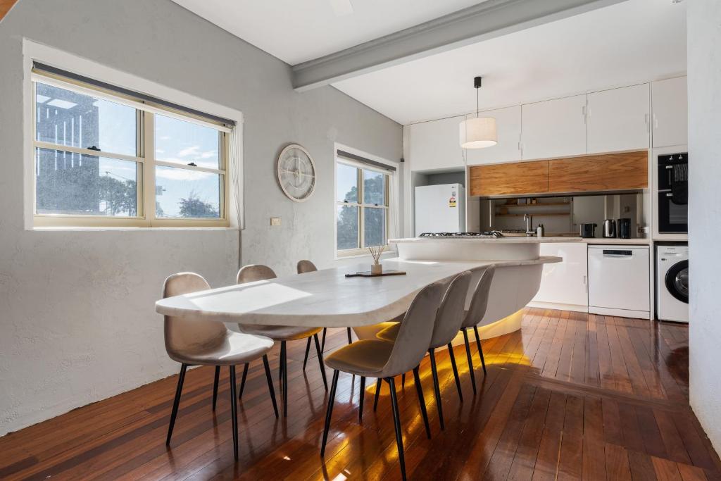 a white kitchen with a white table and chairs at Coastal Haven: Modern 3BR Apartment in Vaucluse in Sydney