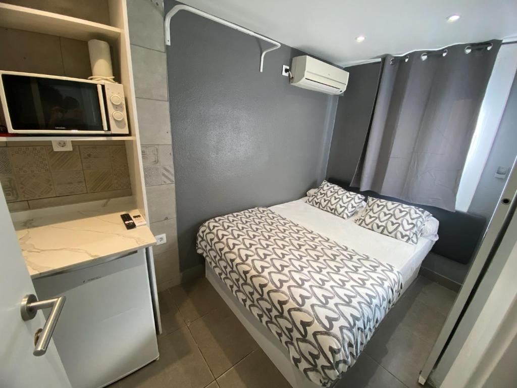 1 dormitorio pequeño con 1 cama y TV en Suites con baño privado frente a la estación de metro L5 Fira Barcelona, en Hospitalet de Llobregat