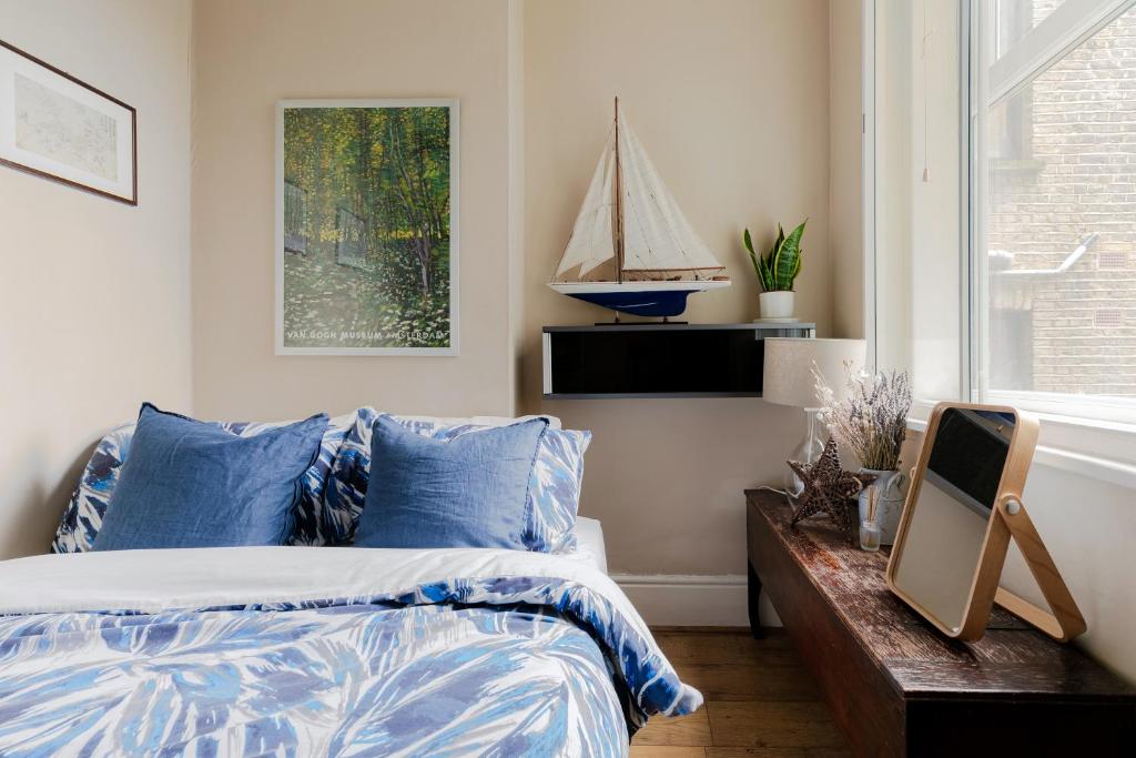 a bedroom with a bed with blue pillows at Stylish Flat with Artistic Flair in Central London in London