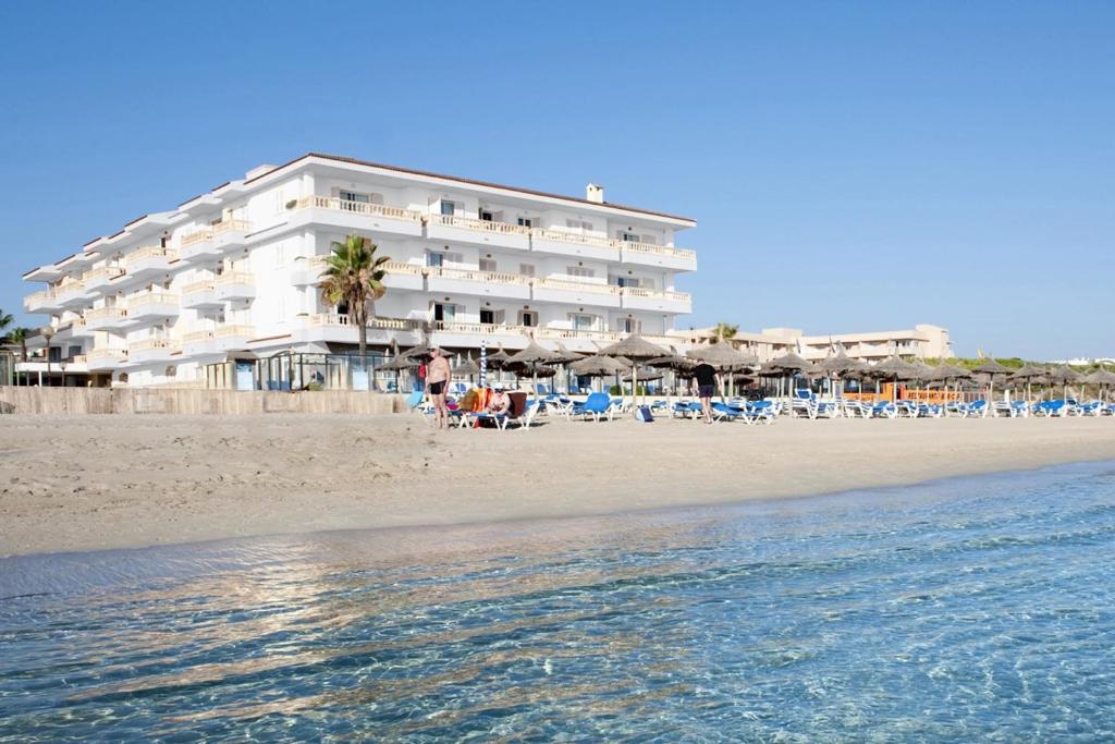 un hotel en la playa con sillas y sombrillas en Grupotel Dunamar en Can Picafort