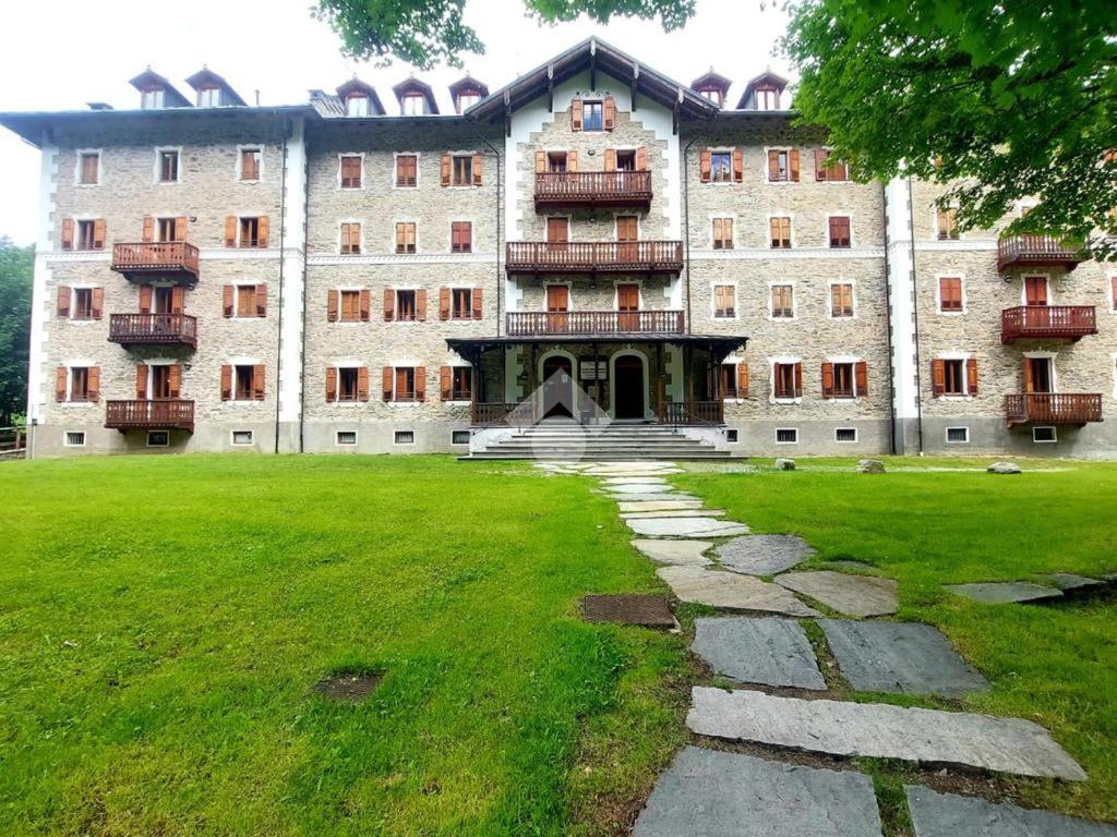 un gran edificio con un césped verde delante de él en Grand Hotel Ceresole Reala Biloapartment, en Ceresole Reale