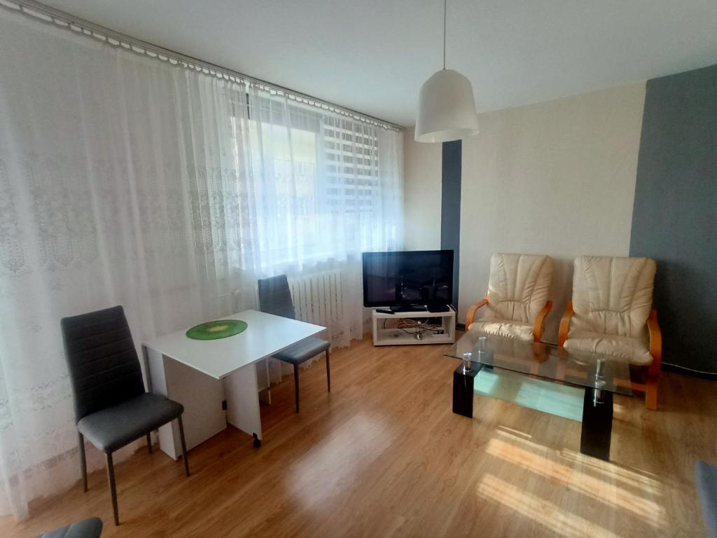 a living room with a table and chairs and a television at Apartament u Anny in Szczytna