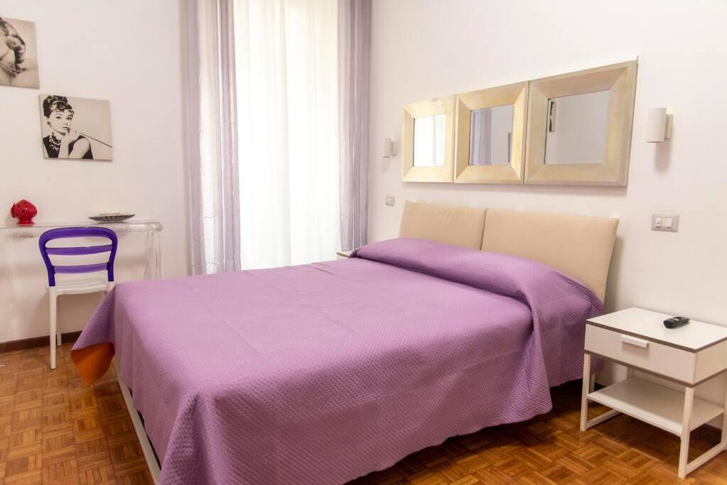 a bedroom with a purple bed and a chair at Nova Domus Colosseo in Rome