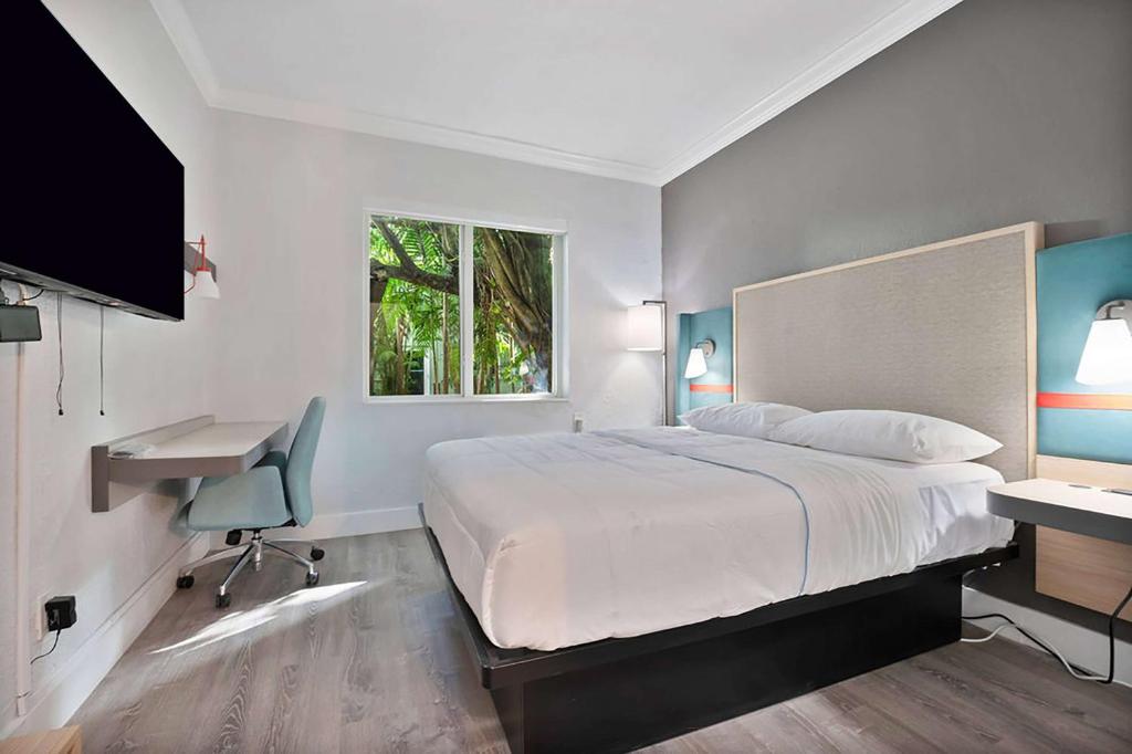 um quarto com uma cama, uma secretária e uma televisão em Garden Hotel Miami Airport, Trademark Collection by Wyndham em Miami