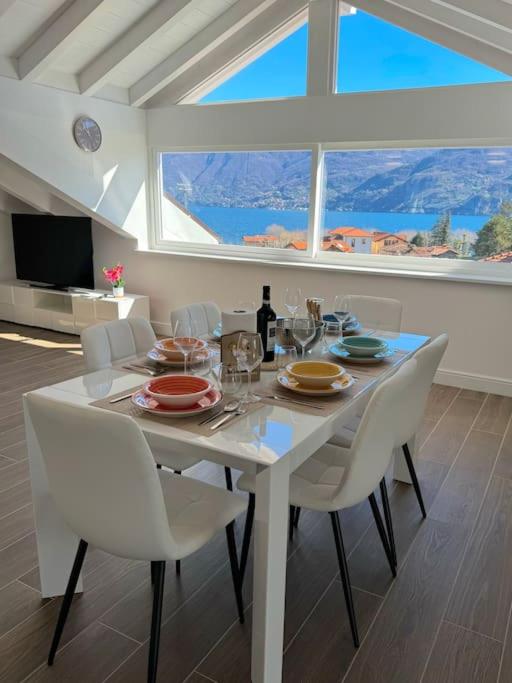 una sala da pranzo con un tavolo bianco e sedie bianche di Apt. Aries - Penthouse Menaggio a Menaggio