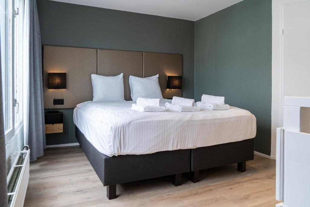 a bedroom with a large bed with white sheets and pillows at Hotel de Duif Lisse - Schiphol in Lisse