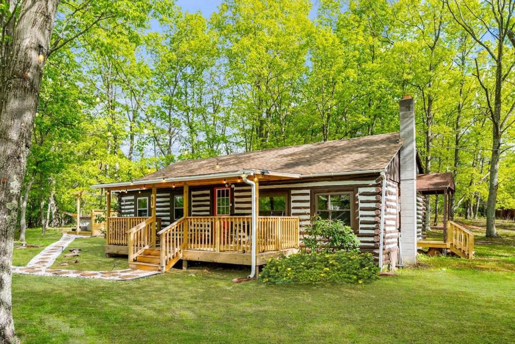 een blokhut met een groot terras in de tuin bij Modernized Log Cabin w Hot Tub Fire Pit & Views in Berkeley Springs