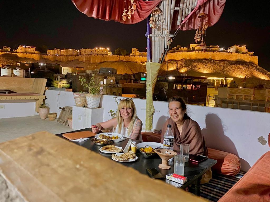 Ein Mann und eine Frau sitzen an einem Tisch mit Essen in der Unterkunft Hotel Murad Haveli Jaisalmer in Jaisalmer