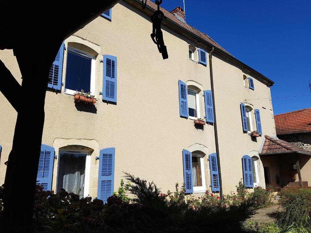 Una casa grande con persianas azules. en La Grange Des Roches Roses, en Anchenoncourt-et-Chazel