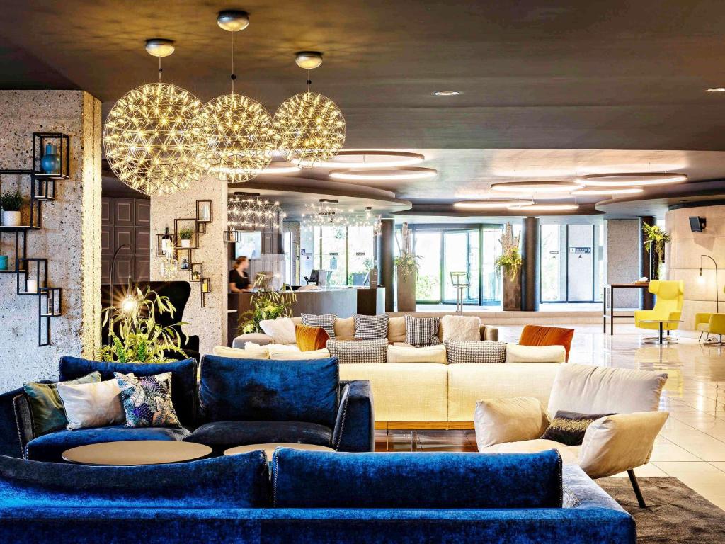 a living room with blue couches and a lobby at Pullman Bordeaux Lac in Bordeaux