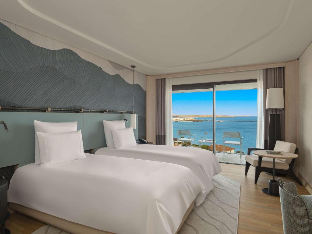 a bedroom with two beds and a view of the ocean at Swissotel Resort And Spa Cesme in Çeşme