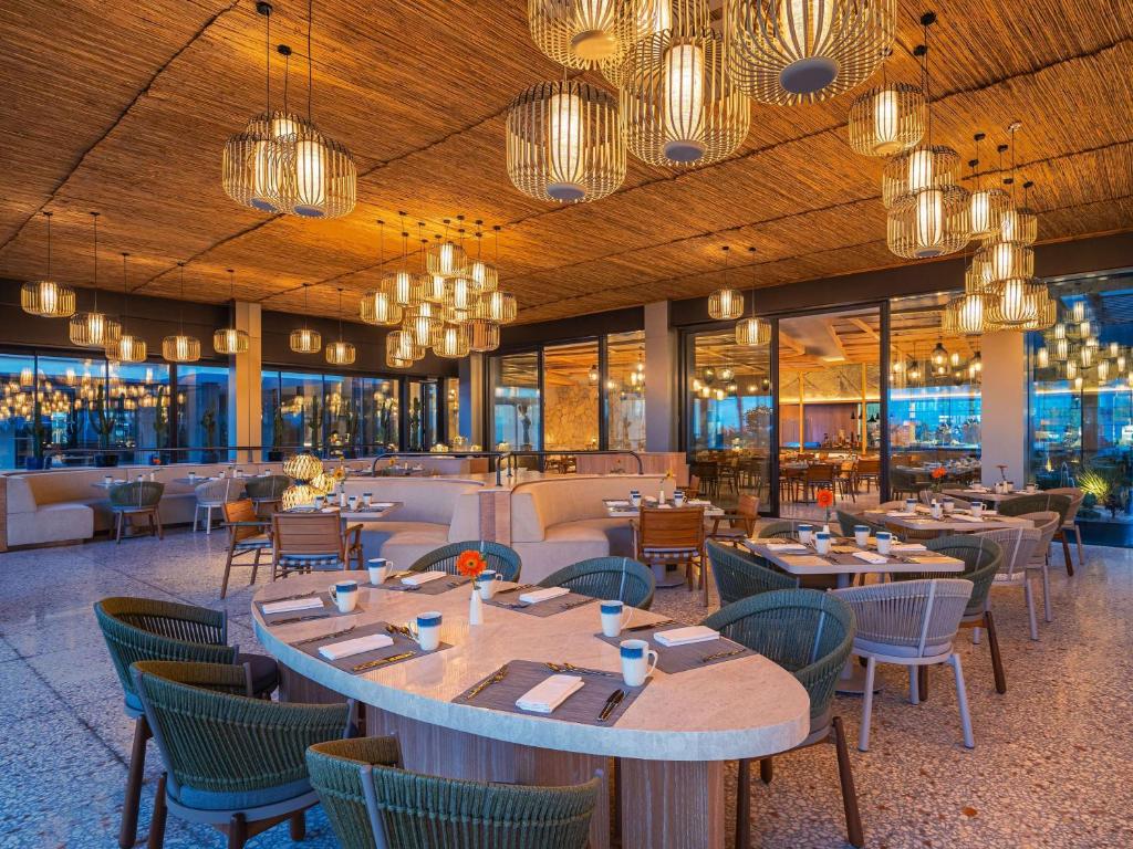 a restaurant with tables and chairs and chandeliers at Swissotel Resort And Spa Cesme in Çeşme