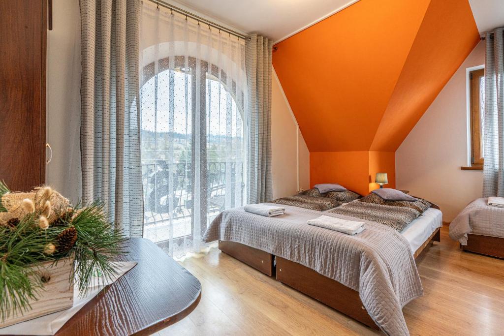 Habitación naranja con 2 camas y ventana grande en Leśny Dworek, en Biały Dunajec
