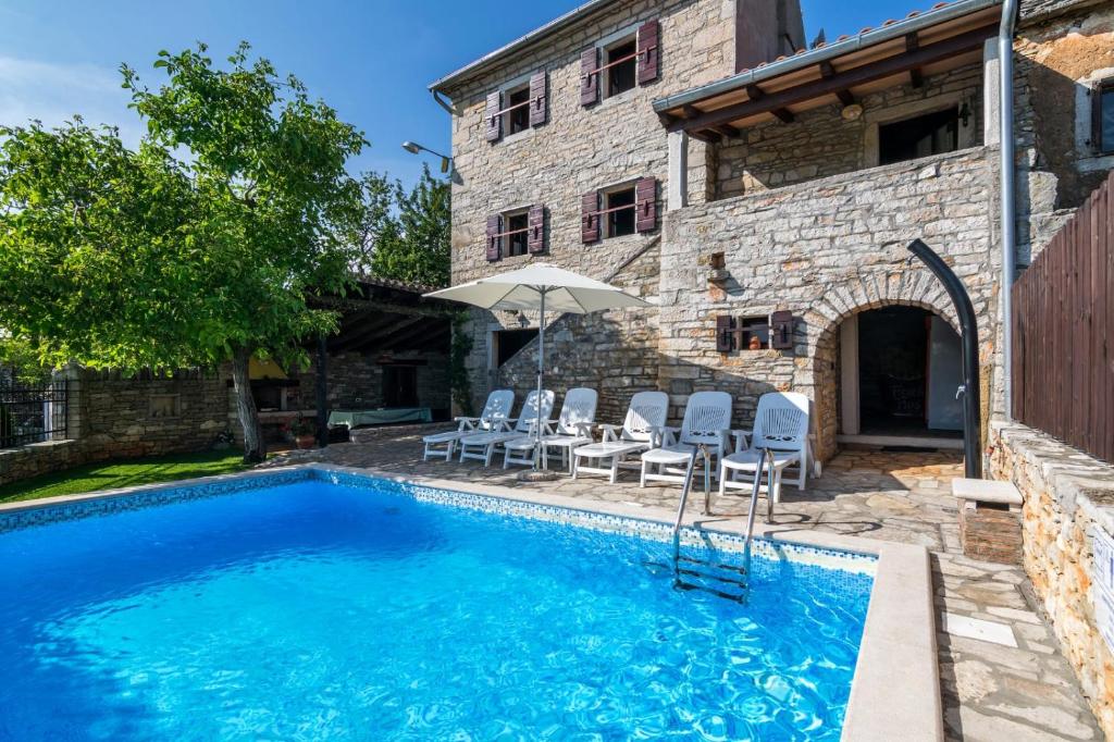 una piscina con sillas y una sombrilla junto a una casa en Rustic Villa Marija with panoramic view in Zrenj, en Zrenj