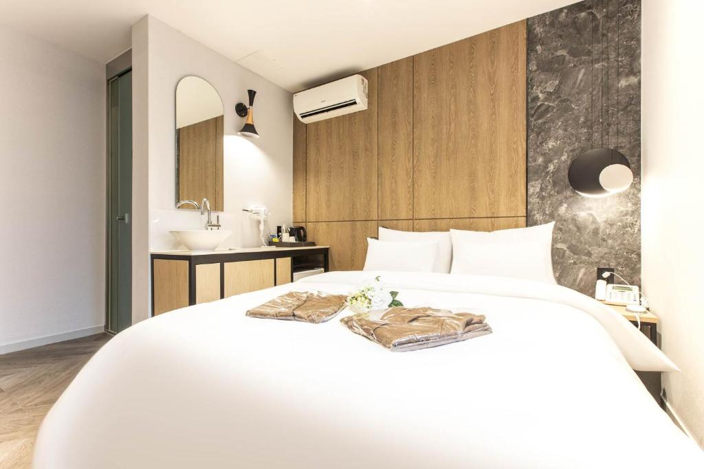 1 dormitorio con cama blanca y lavamanos en Brown Dot Hotel Incheon Jakjeon en Incheon