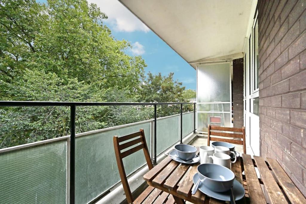 a balcony with a wooden table and chairs on a balcony at Regents Park- UCL, Apartment with Balcony in London