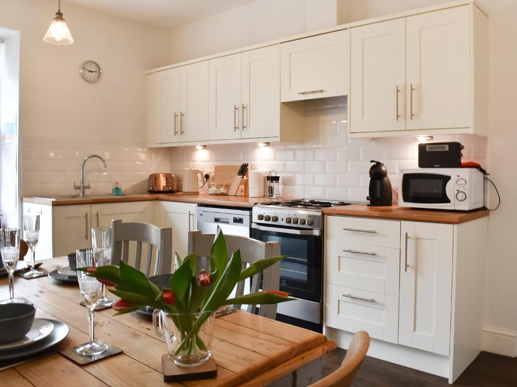 cocina con armarios blancos y mesa de madera en Belmont Apartment, en Arnside