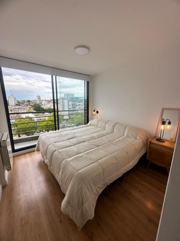 ein großes Bett in einem Zimmer mit einem großen Fenster in der Unterkunft nardos suites in Balcarce
