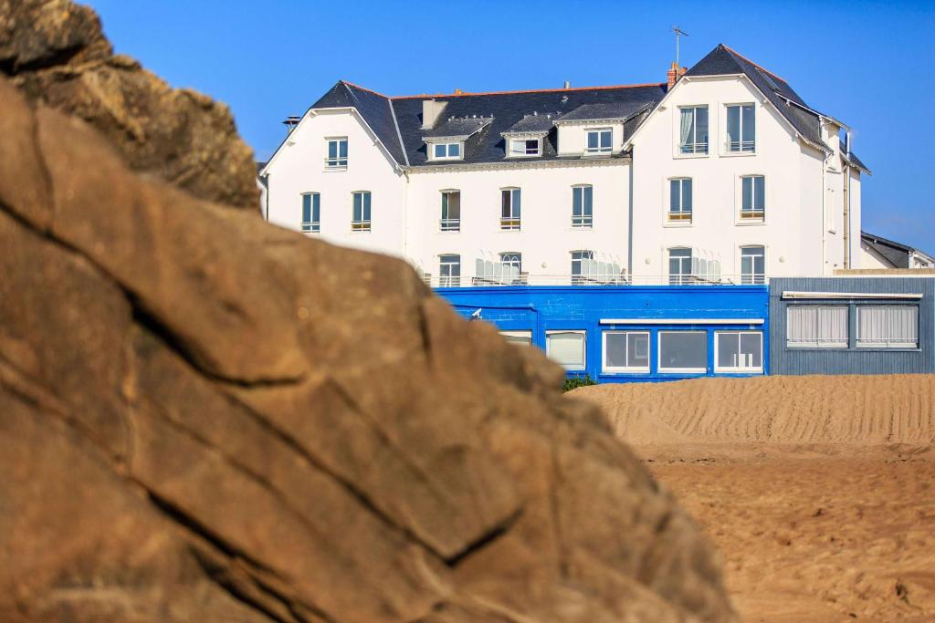 um edifício na praia com uma grande rocha em Best Western Hotel De La Plage Saint Marc sur Mer em Saint-Nazaire