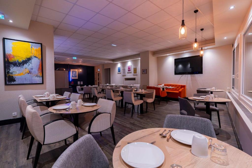 a restaurant with tables and chairs and a flat screen tv at Best Western Hotel De La Plage Saint Marc sur Mer in Saint-Nazaire