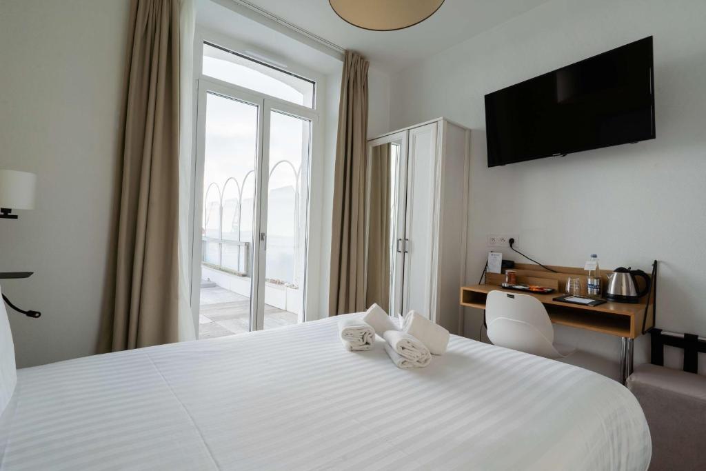 a hotel room with a white bed with a window at Best Western Hotel De La Plage Saint Marc sur Mer in Saint-Nazaire