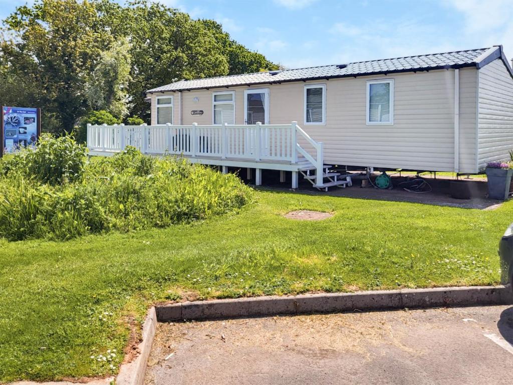 a mobile home with a porch and a yard at Country View C50 in Blue Anchor